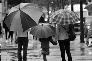 A black and white photo of a family with umbrellas